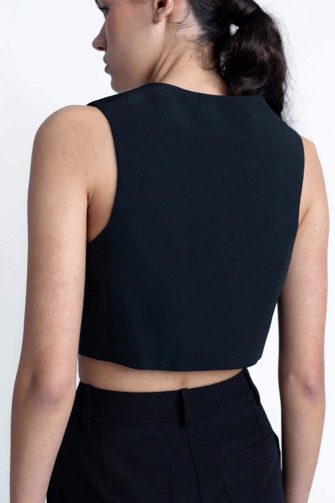 Vue arrière d'un modèle portant le Pantalon Noir Fluide Femme Élégant à Pinces en Polyester Recyclé, mettant en valeur sa coupe stylée.