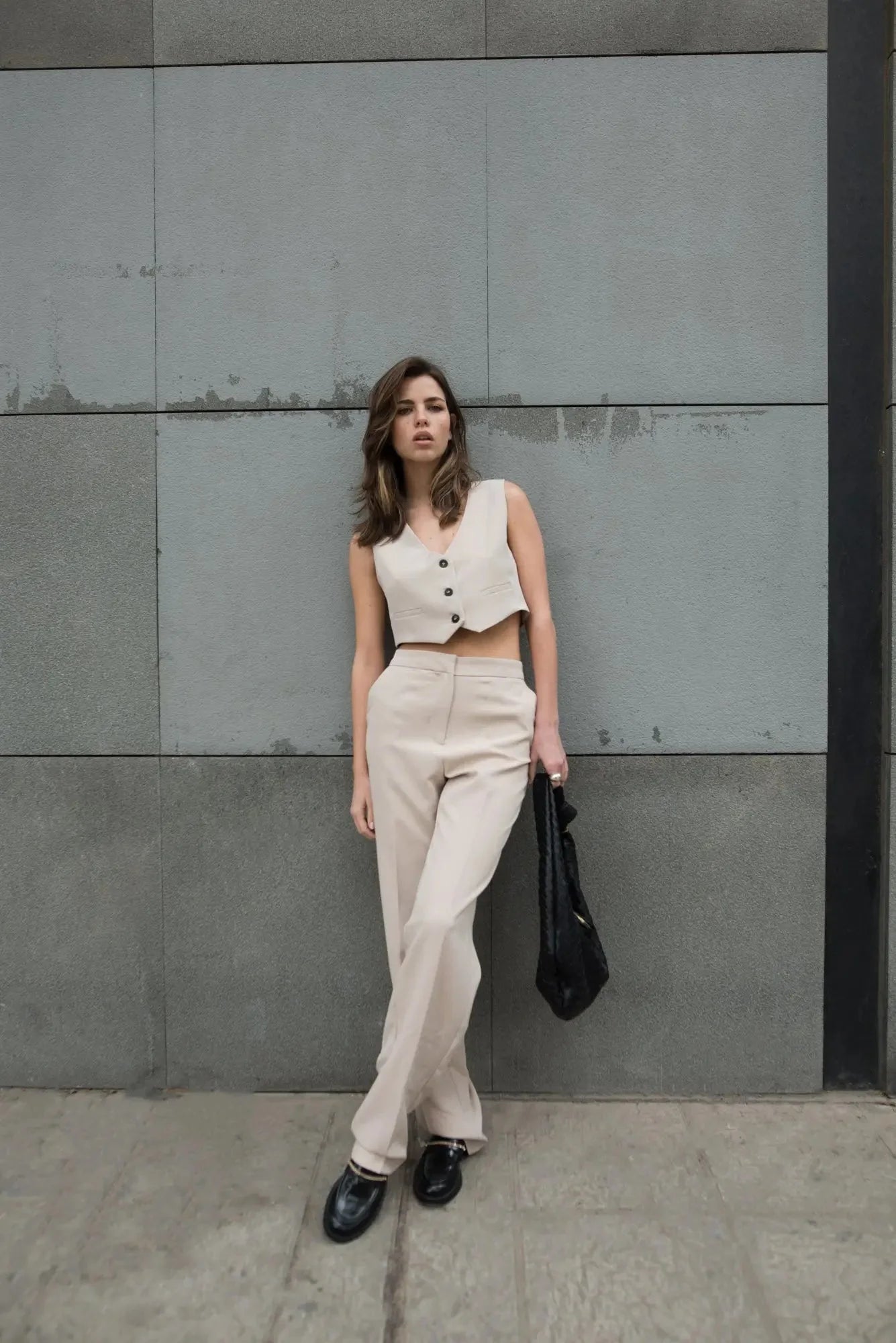 Femme portant un ensemble beige sans manches et pantalon large avec sac noir