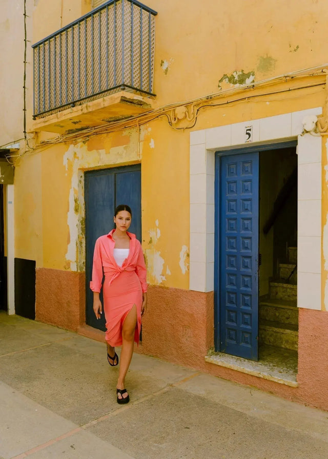 Femme portant une jupe midi rose corail en tissu fluide avec haut rose corail