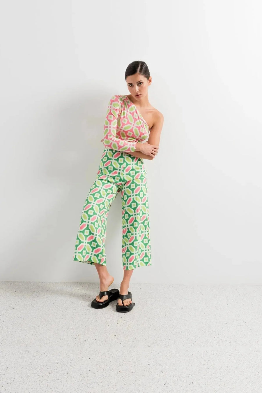 Femme affichant une attitude décontractée dans un body femme asymétrique manches longues rose et vert, associée à un bas coordonné.