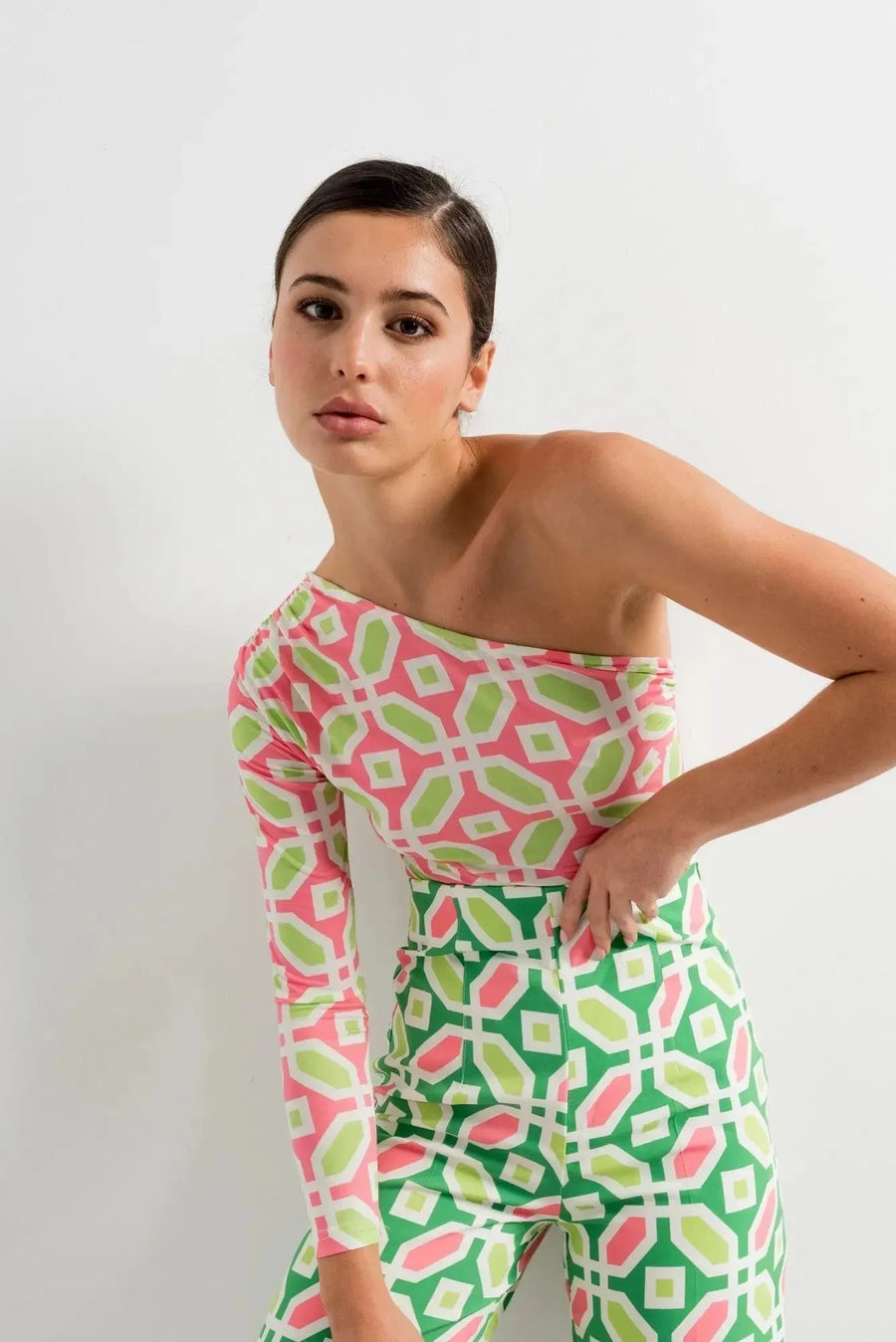 Femme élégante en body femme asymétrique manches longues avec un imprimé géométrique en rose et vert, affichant une pose stylée.