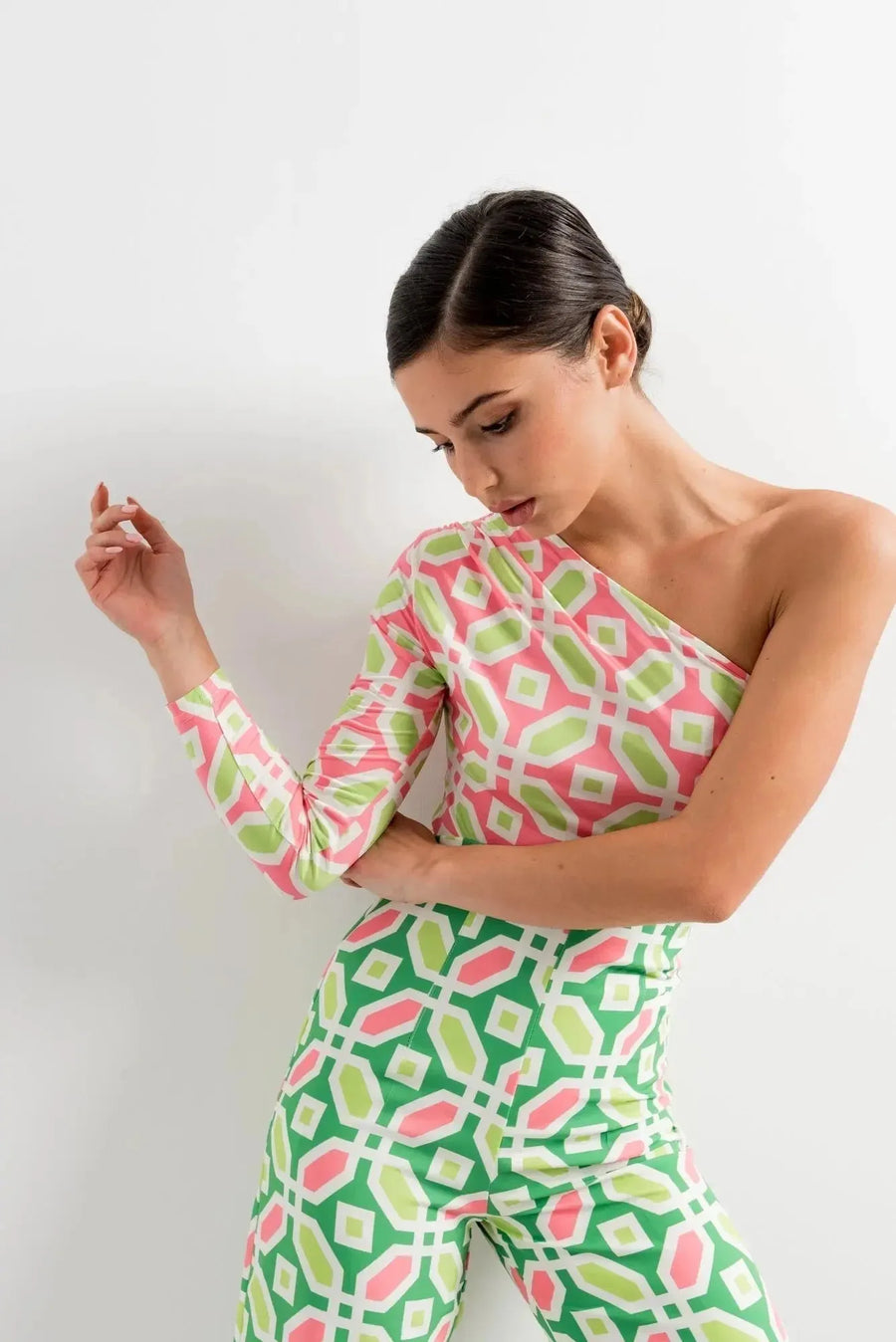 Modèle portant un body femme asymétrique manches longues imprimé géométrique rose/vert, mettant en avant une allure graphique et féminine.