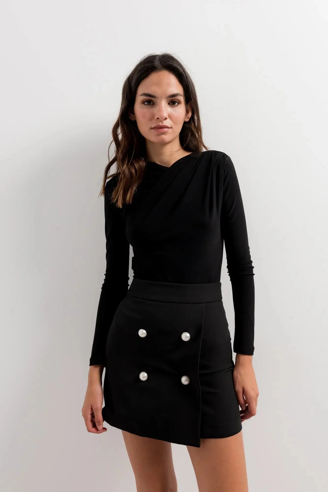 Ensemble mini jupe avec touche d’élégance, haut noir à manches longues et jupe noire à boutons blancs