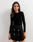 Femme affichant une mini jupe chic et polyvalente avec boutons en perle, style décontracté avec un haut noir.
