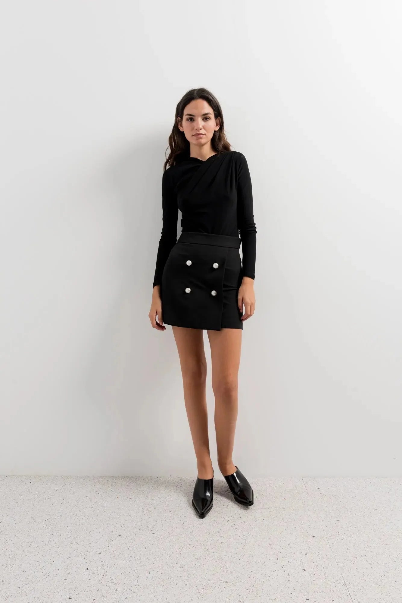Ensemble mini jupe avec une touche d’élégance, top noir à manches longues et boutons blancs