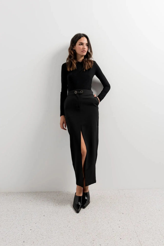 Femme en jupe longue fendue devant, modèle Jupe Boutonnée Midi Fendue Noir - Élégance Confortable Pour Toutes Occasions, affichant un style chic avec un haut noir.