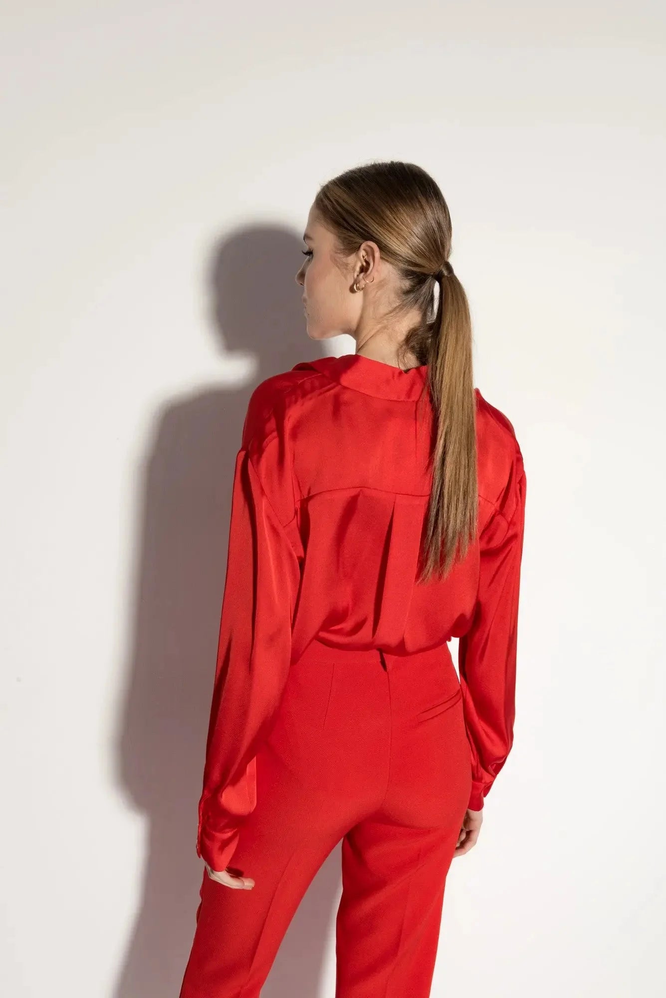 Femme portant un ensemble pantalon à ourlet fendu en satin rouge élégant