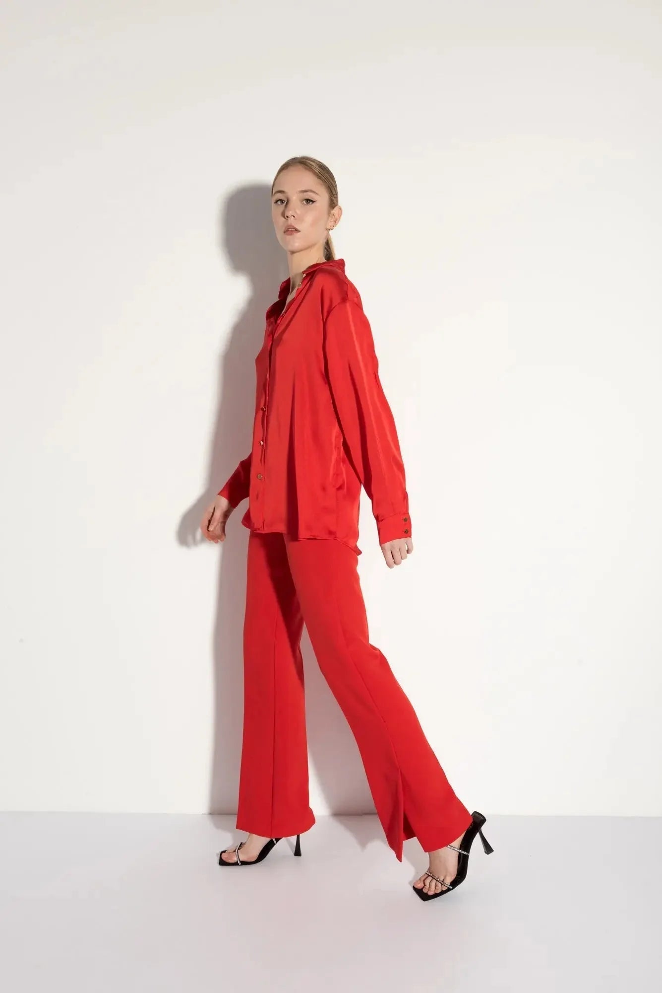 Femme portant un ensemble pantalon à ourlet fendu en satin rouge et sandales à talons