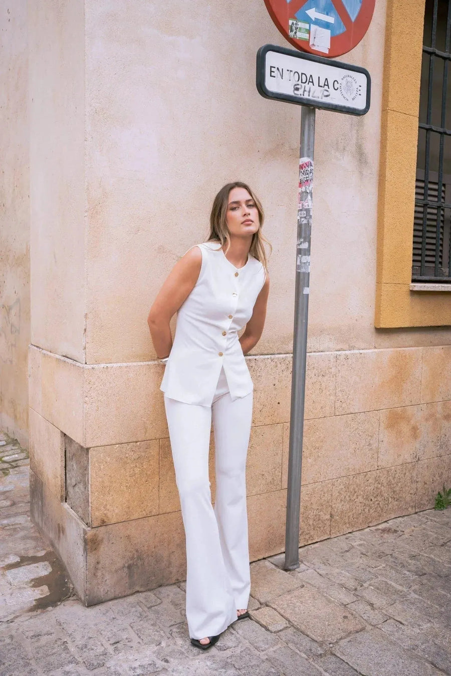 Femme en vest blanc chic et pantalon évasé dans l’ensemble blanc chic femme