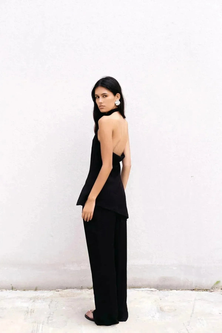 Femme avec une pose stylée, portant un top noir et pantalon fluide noir taille haute, l'allié idéal pour une allure chic, pantalon fluide femme.