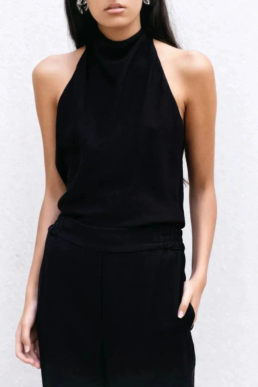 Close-up d'une femme en haut noir et pantalon fluide noir taille haute, parfait pour un look chic et moderne, pantalon fluide femme.