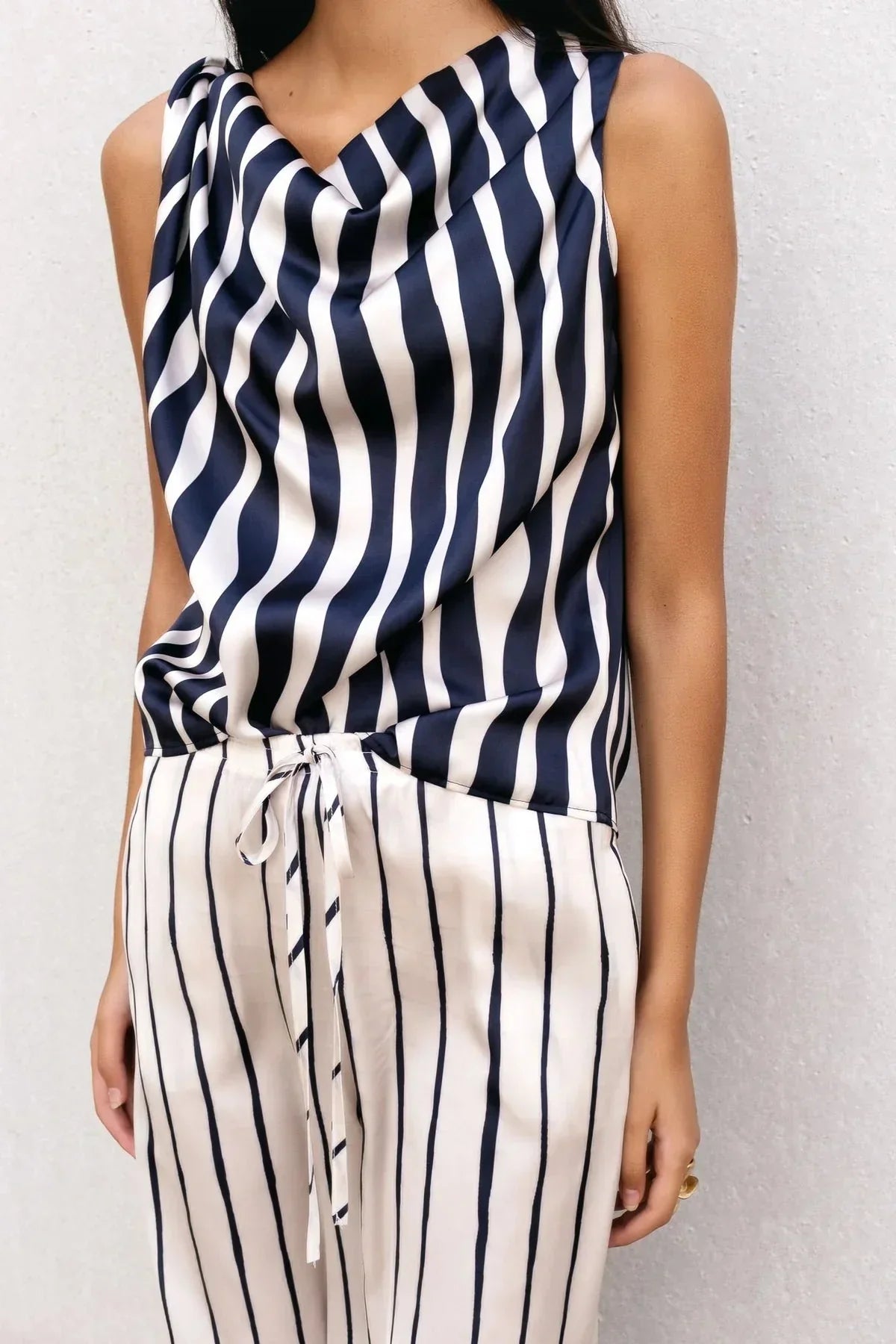 Détail d'une femme en pantalon à rayures femme fluide, mettant en avant la taille élastique ajustable par cordon et le motif à rayures.