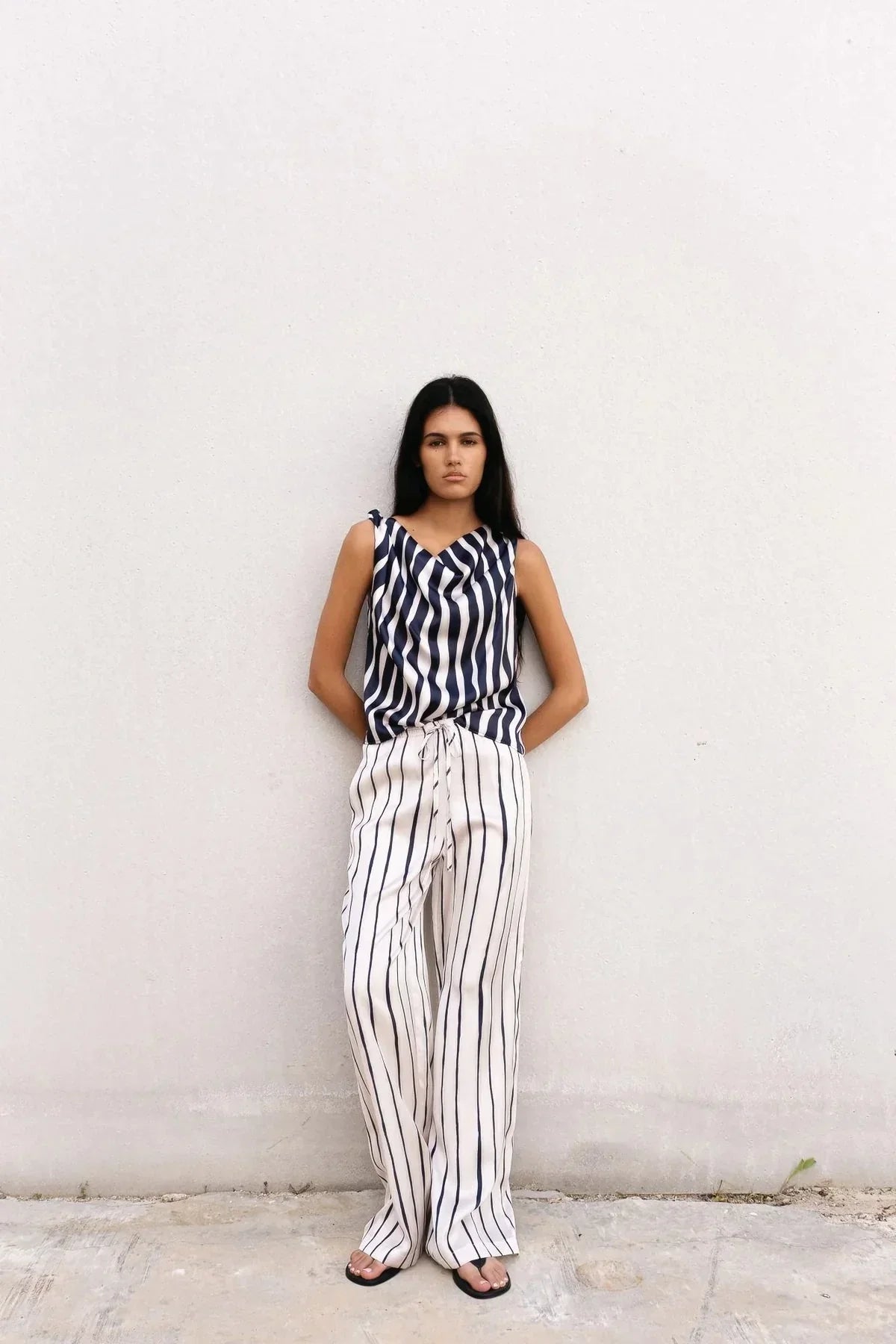 Femme portant un ensemble pantalon fluide rayé bleu marine et blanc, style élégant