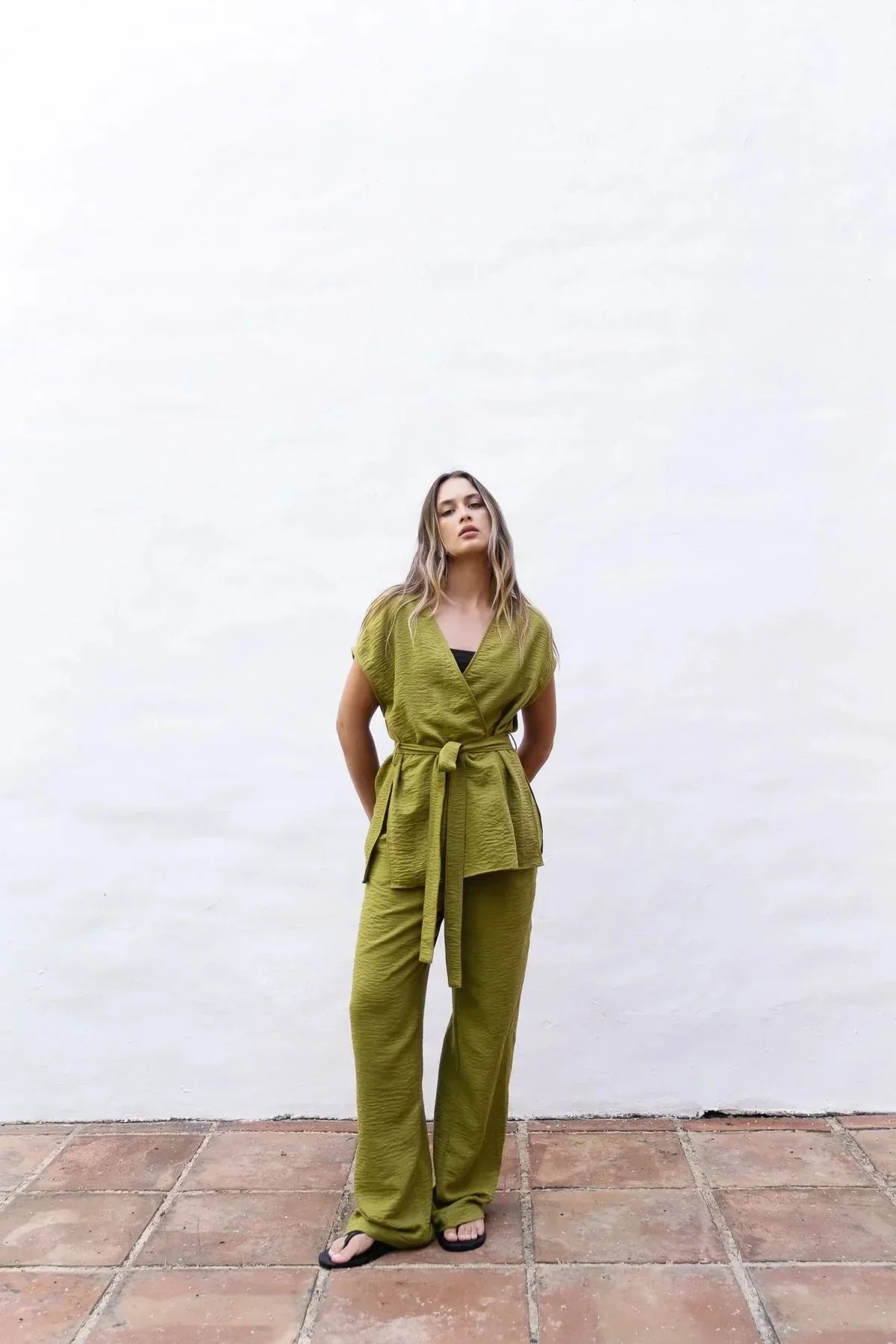 Femme portant un ensemble pantalon fluide vert olive et gilet en satin