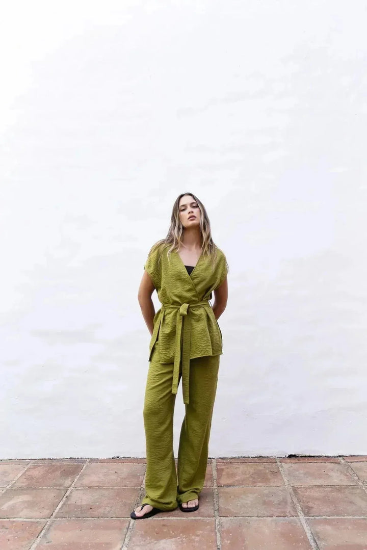 Modèle portant un pantalon fluide vert olive femme avec taille élastiquée haute, une touche de confort et style été.