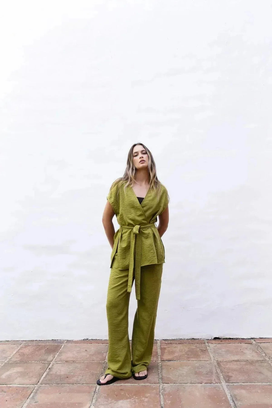 Modèle portant un pantalon fluide vert olive femme avec taille élastiquée haute, une touche de confort et style été.