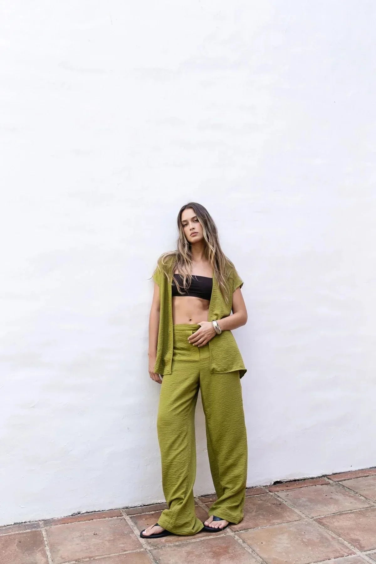 Femme portant un ensemble pantalon fluide vert olive et gilet en satin, look décontracté