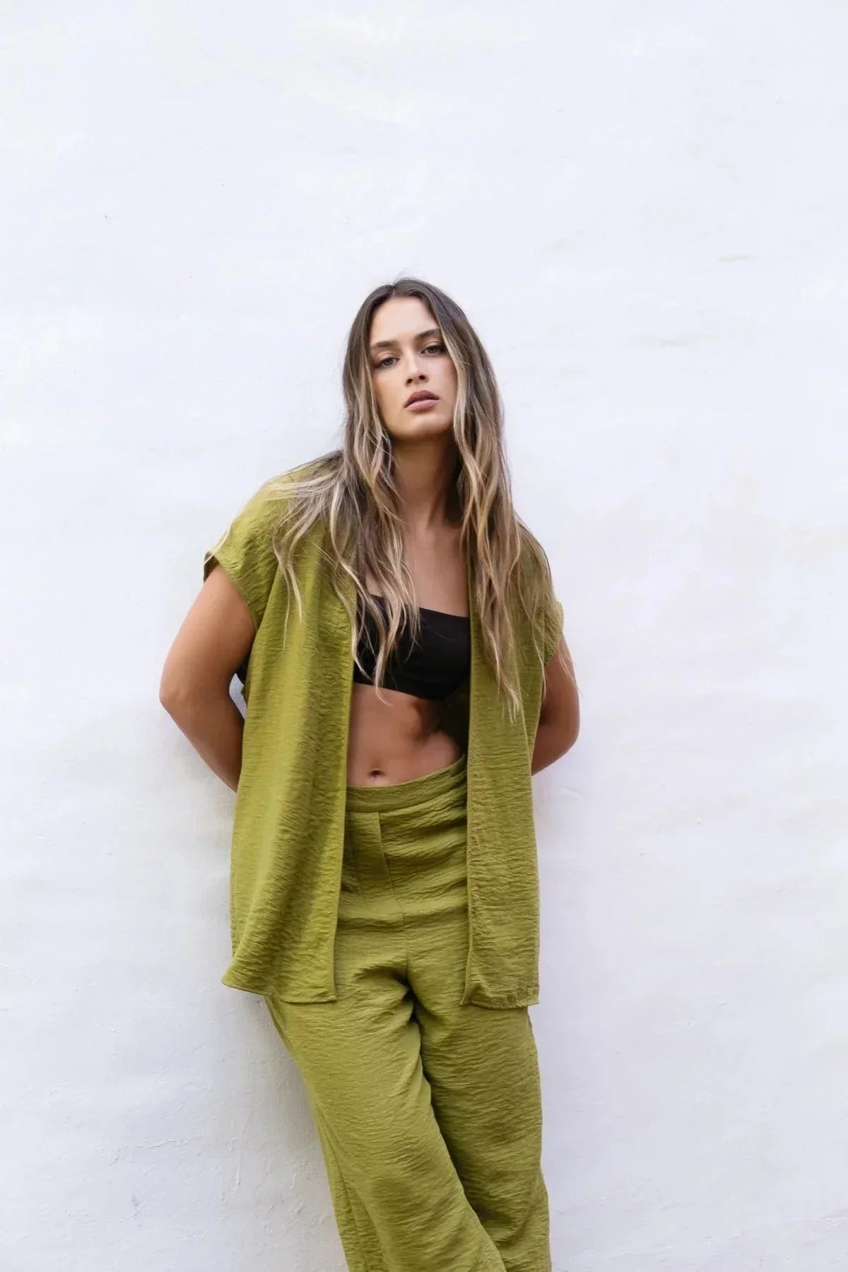 Femme portant un ensemble pantalon fluide vert olive et gilet en satin, look élégant