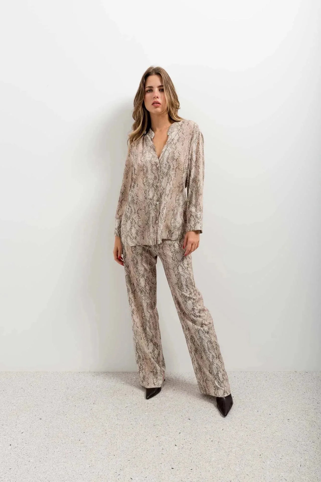 Modèle individuel dans un ensemble pantalon large imprimé animal serpent, le pantalon serpent ajoute une touche audacieuse à son look.