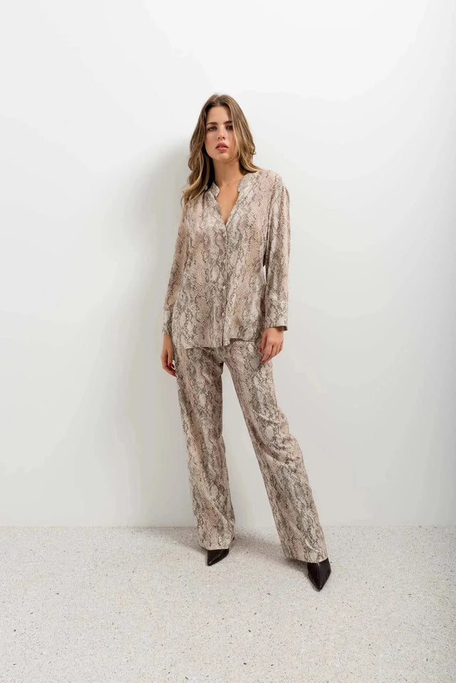 Modèle individuel dans un ensemble pantalon large imprimé animal serpent, le pantalon serpent ajoute une touche audacieuse à son look.