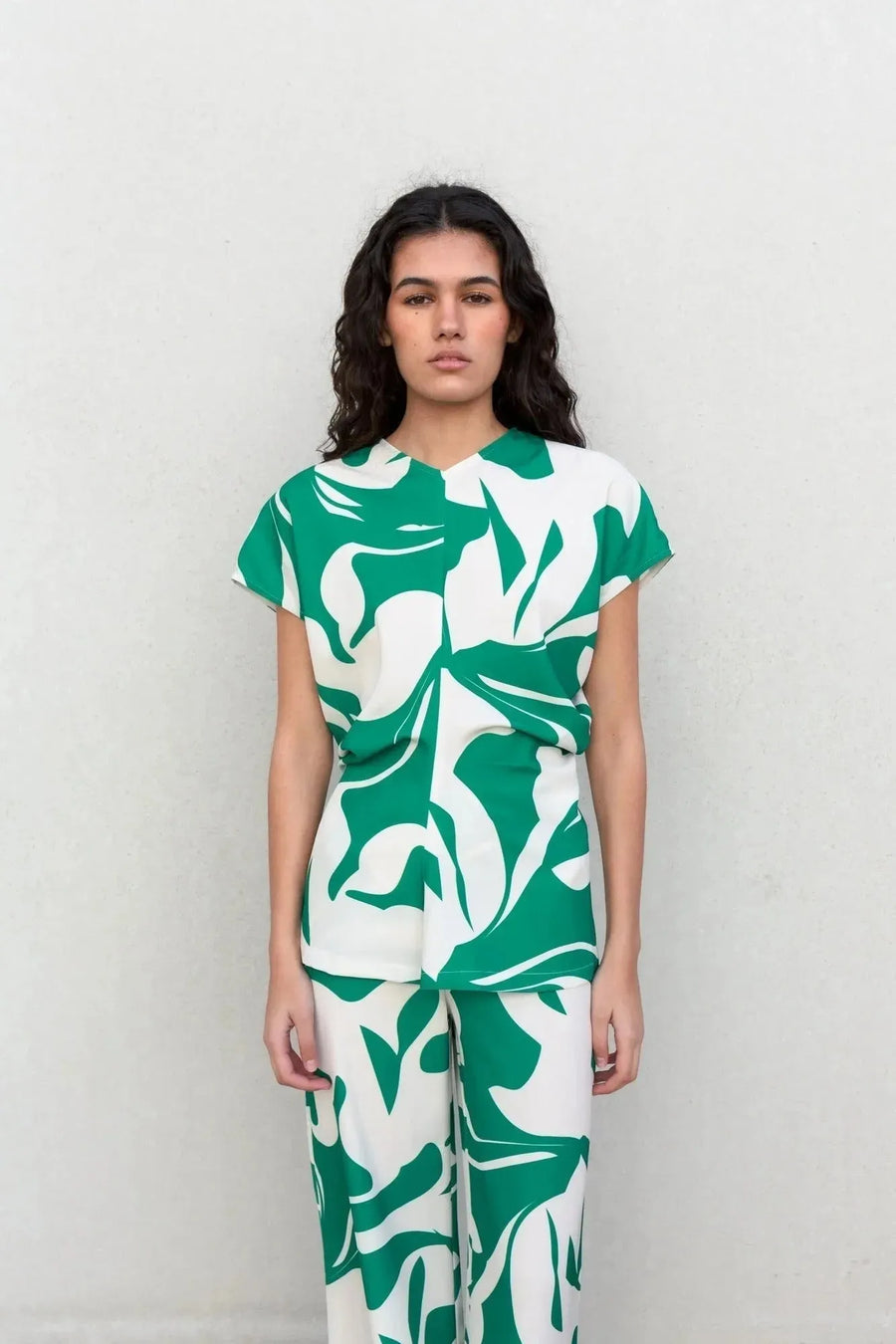 Modèle portant un ensemble pantalon palazzo imprimé floral vert et blanc, mettant en avant le pantalon palazzo femme avec un design moderne et stylé.