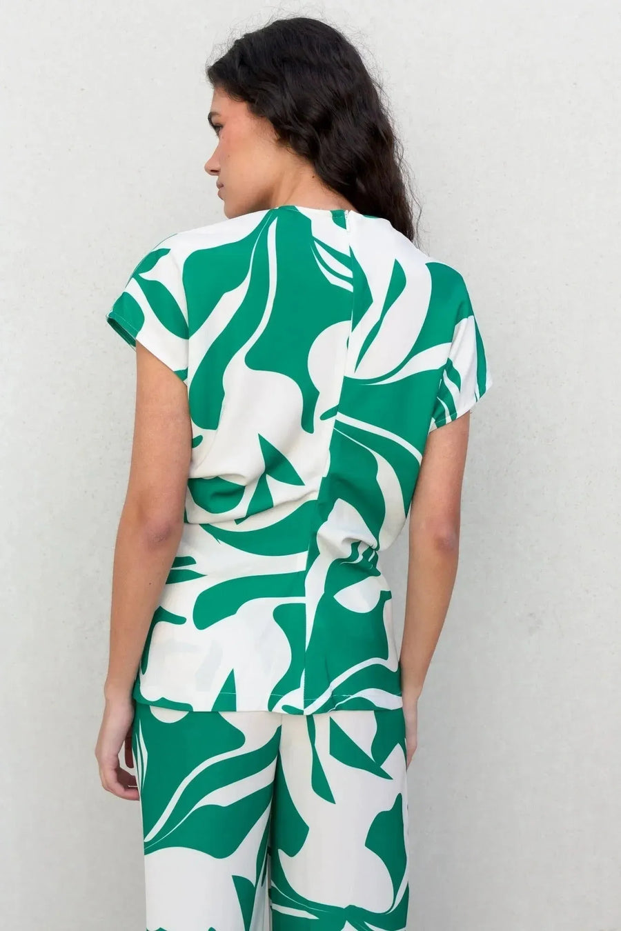 Femme portant un ensemble avec un pantalon palazzo imprimé floral vert et blanc, mettant en évidence le pantalon palazzo femme avec une coupe moderne.