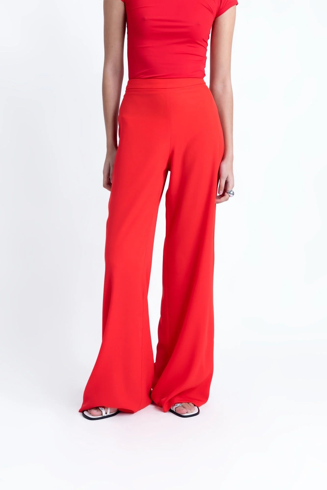 Photo d’une personne portant un ensemble pantalon palazzo rouge avec top rouge et sandales blanches