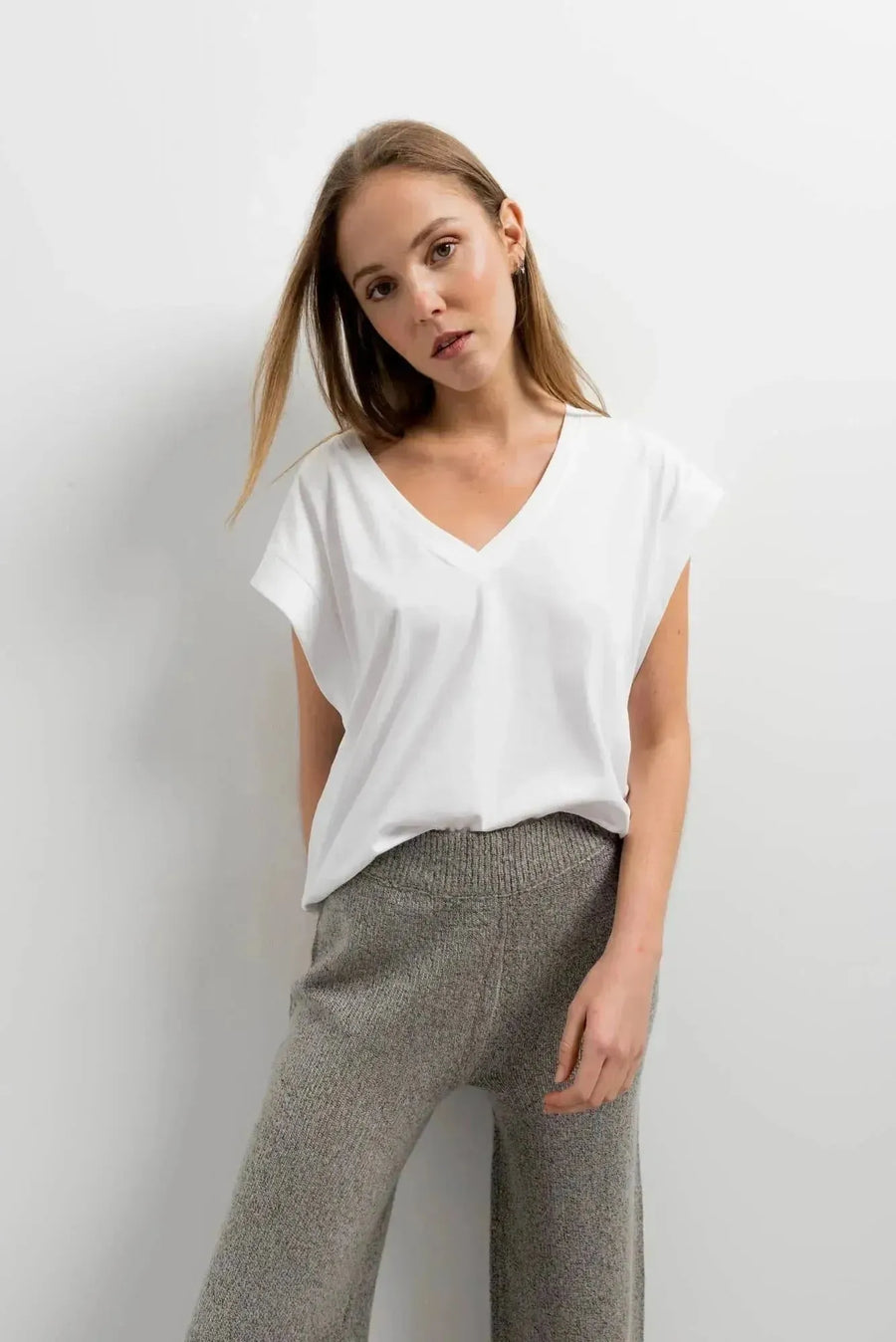 Femme posant avec un pantalon tricot à jambes larges couleur gris et un t-shirt blanc, un choix idéal pour un look décontracté. Pantalon tricot femme à la fois tendance et confortable.