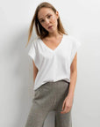 Femme posant avec un pantalon tricot à jambes larges couleur gris et un t-shirt blanc, un choix idéal pour un look décontracté. Pantalon tricot femme à la fois tendance et confortable.