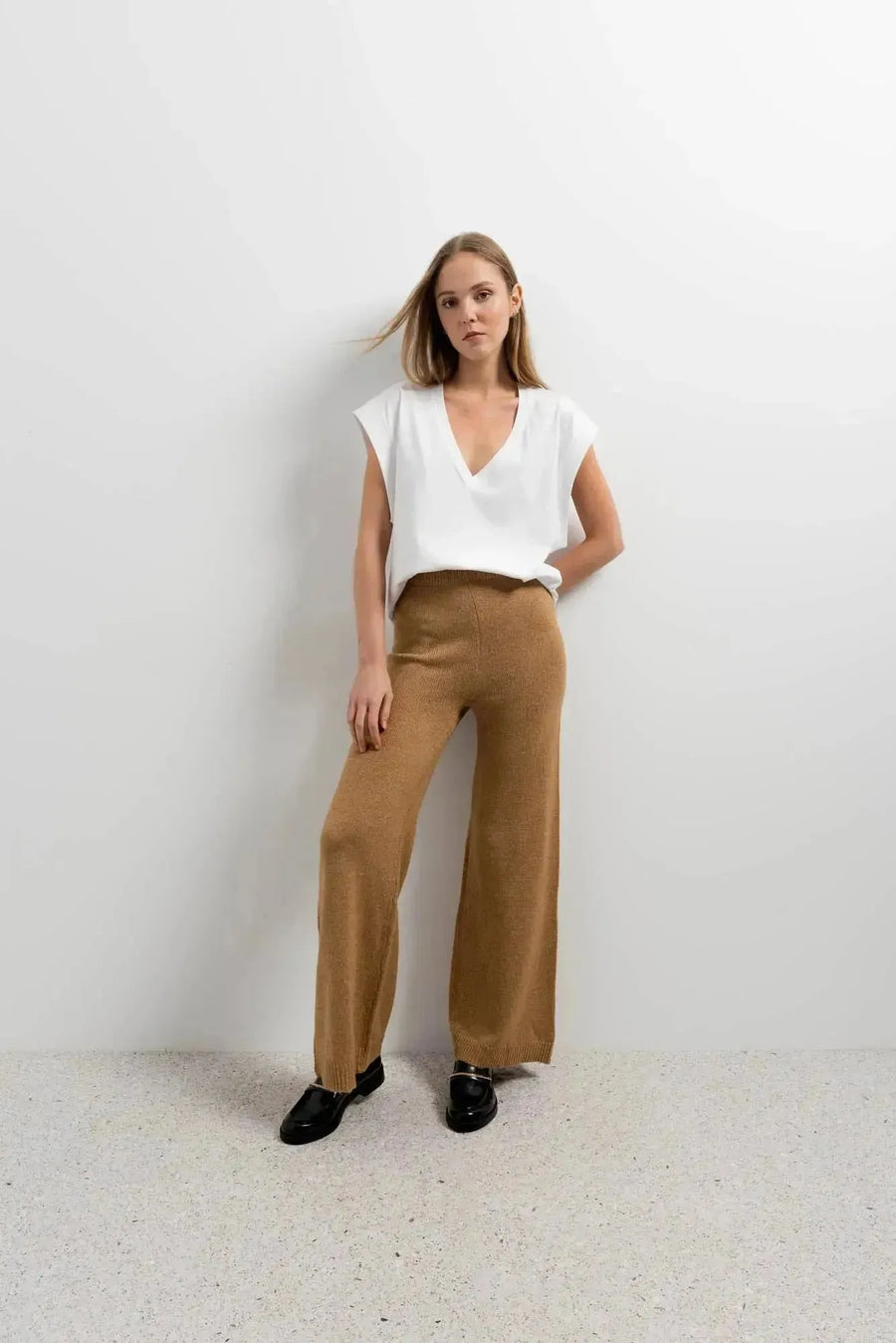 Modèle féminin en pantalon tricot à jambes larges couleur camel et t-shirt blanc, alliant style moderne et confort. Parfait pantalon tricot femme pour diverses occasions.