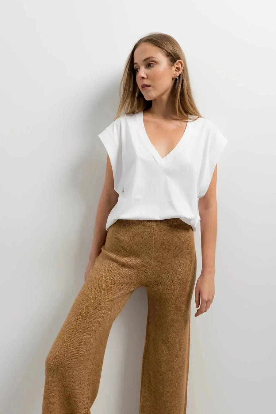 Femme en pantalon tricot à jambes larges camel avec un t-shirt blanc, conçu pour un confort optimal tout en restant chic. Idéal pour le pantalon tricot femme.