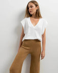 Femme en pantalon tricot à jambes larges camel avec un t-shirt blanc, conçu pour un confort optimal tout en restant chic. Idéal pour le pantalon tricot femme.