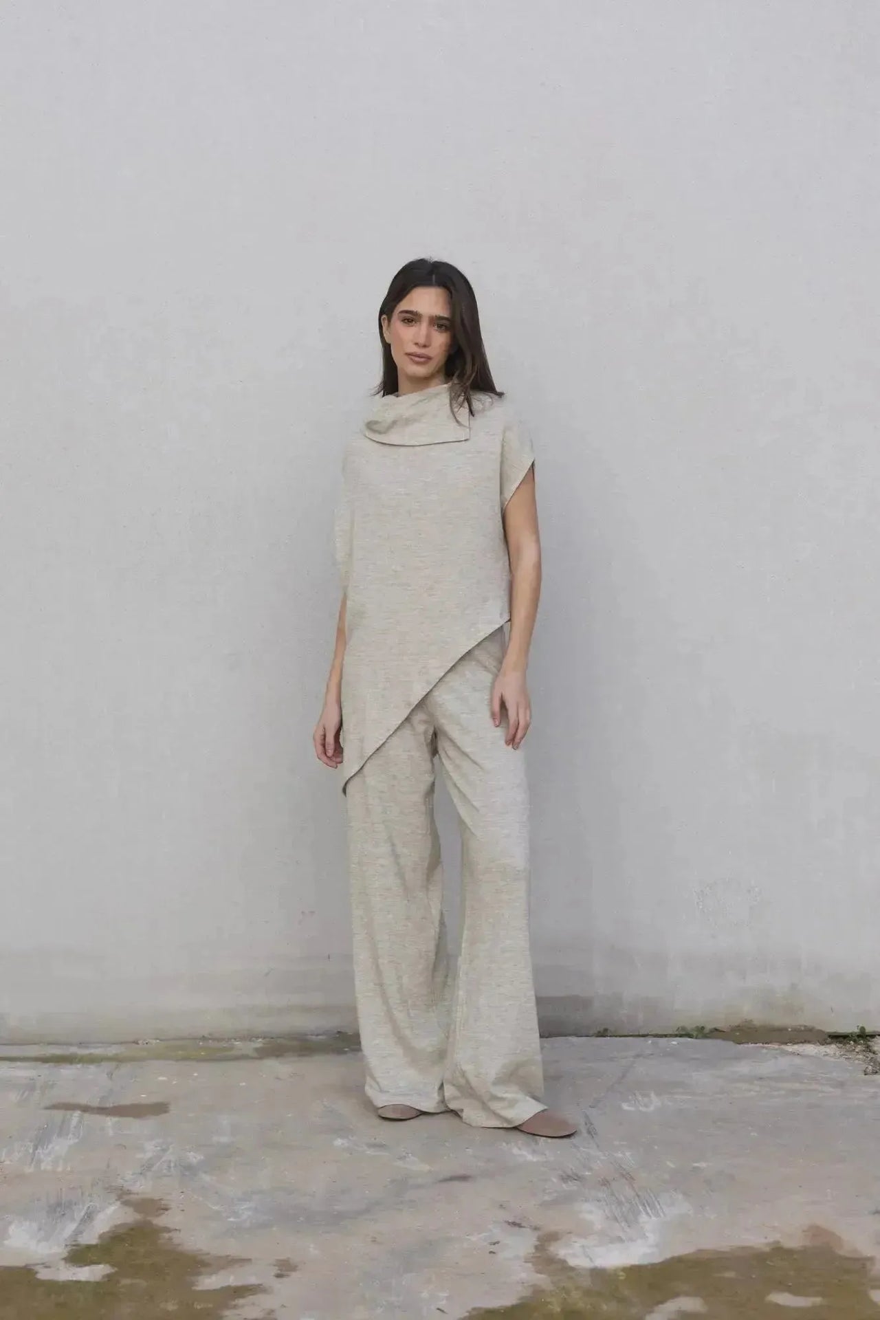 Vue de face d'une femme en pull cape femme beige avec pantalon large, parfait mélange de sophistication et confort.