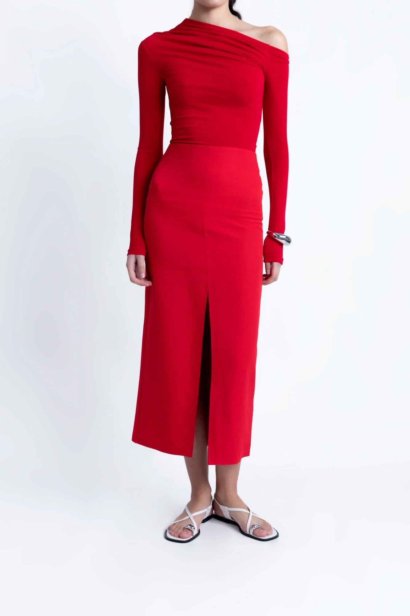 Ensemble t-shirt asymétrique rouge et jupe assortie avec décolleté et sandales blanches