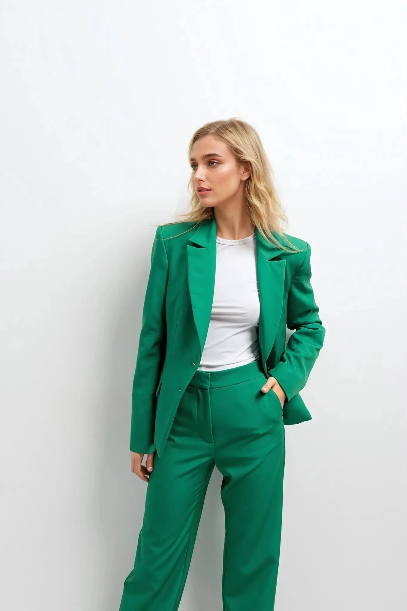 Femme portant un ensemble tailleur pantalon vert avec un haut blanc