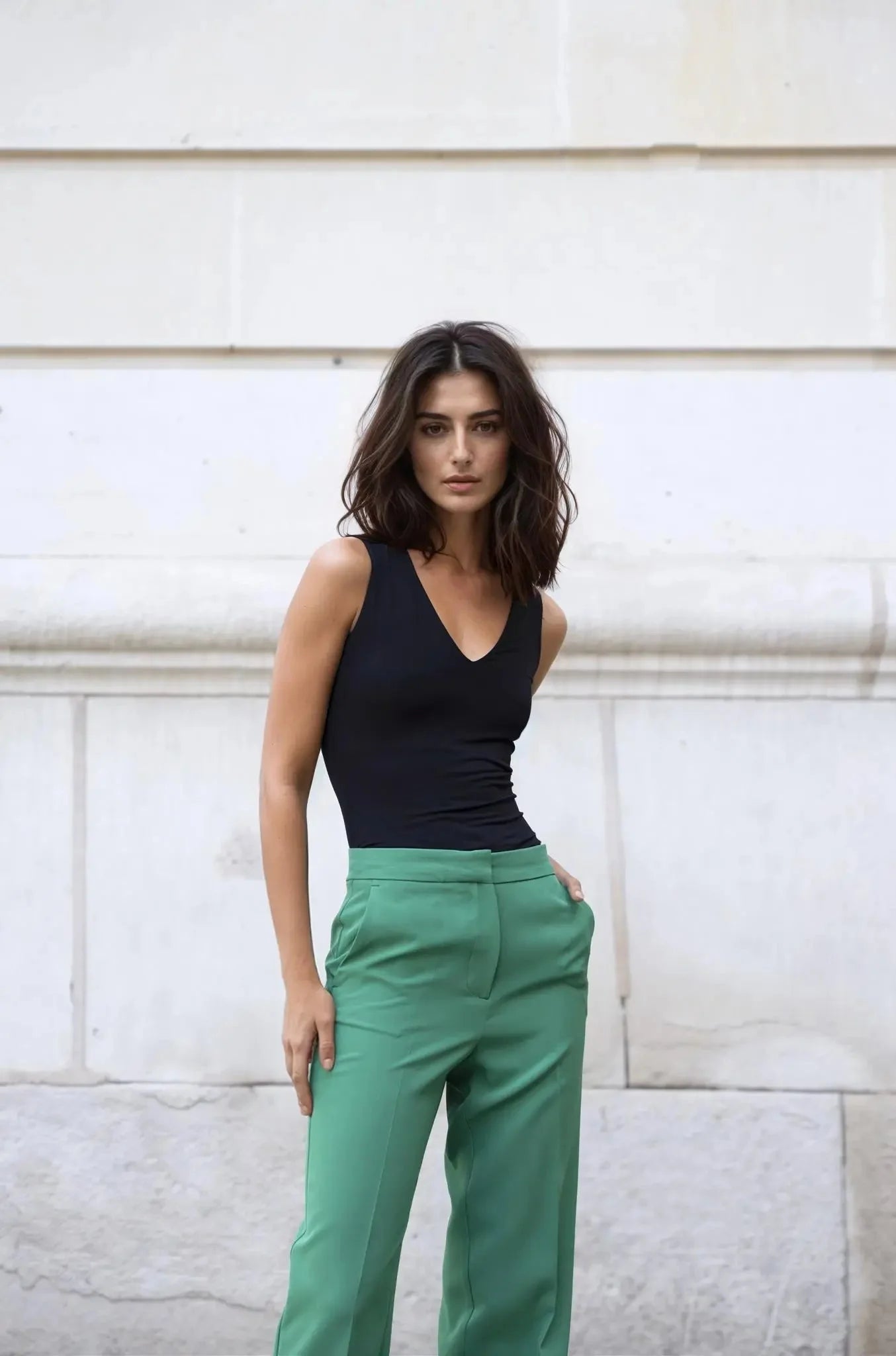 Femme portant un ensemble tailleur pantalon vert et haut sans manches noir
