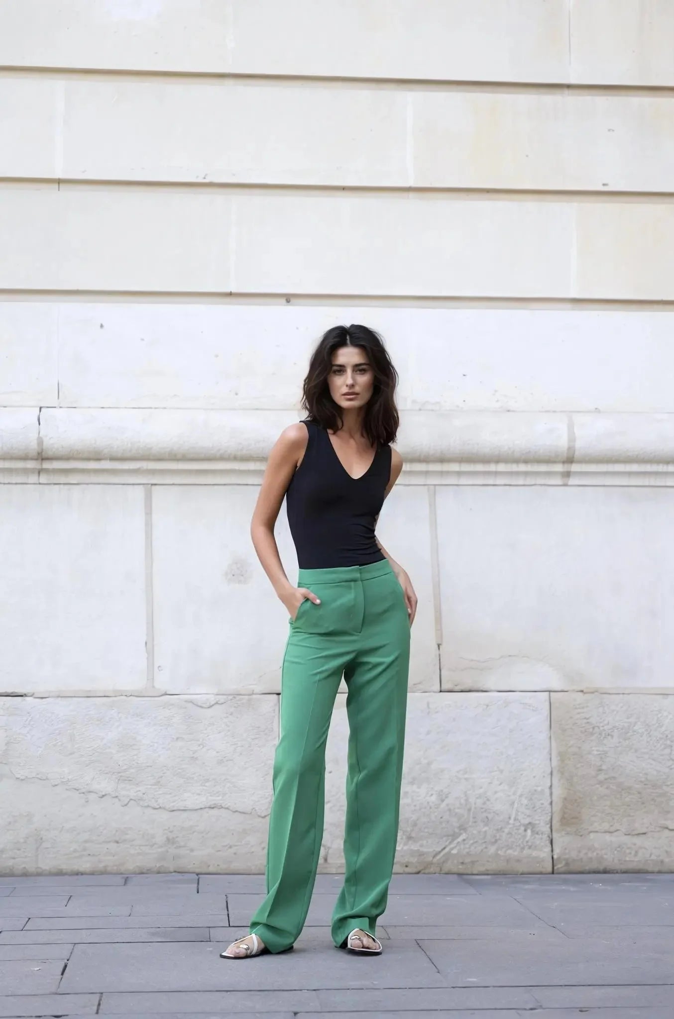 Femme portant un haut noir en V et un pantalon vert large dans l’ensemble tailleur pantalon vert