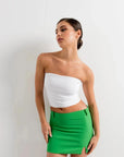 Modèle portant une mini jupe verte taille haute avec fente latérale pour femme, affichant un look élégant et moderne.