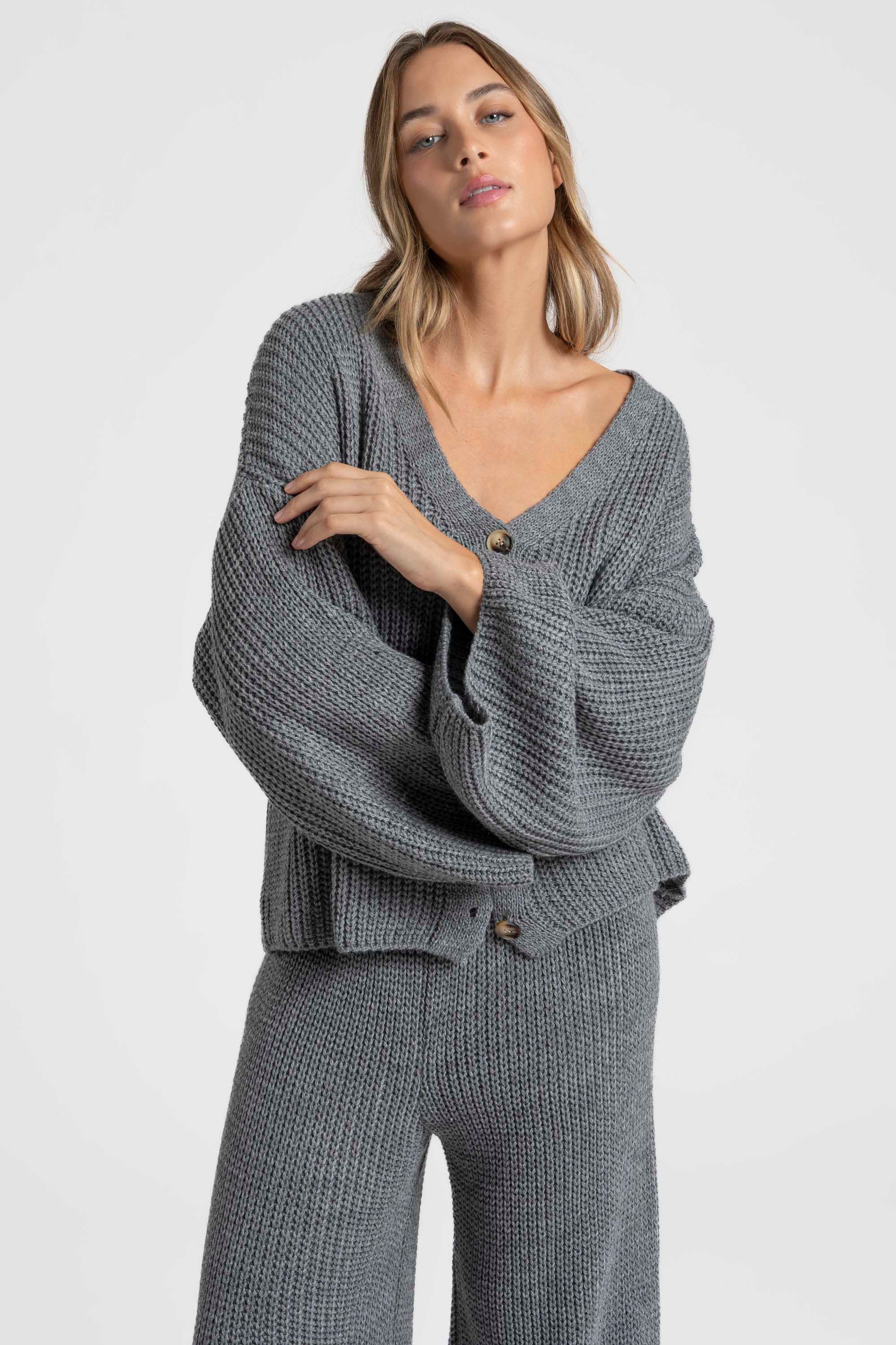 Femme debout dans un ensemble maille femme italien gris, affichant une allure élégante.