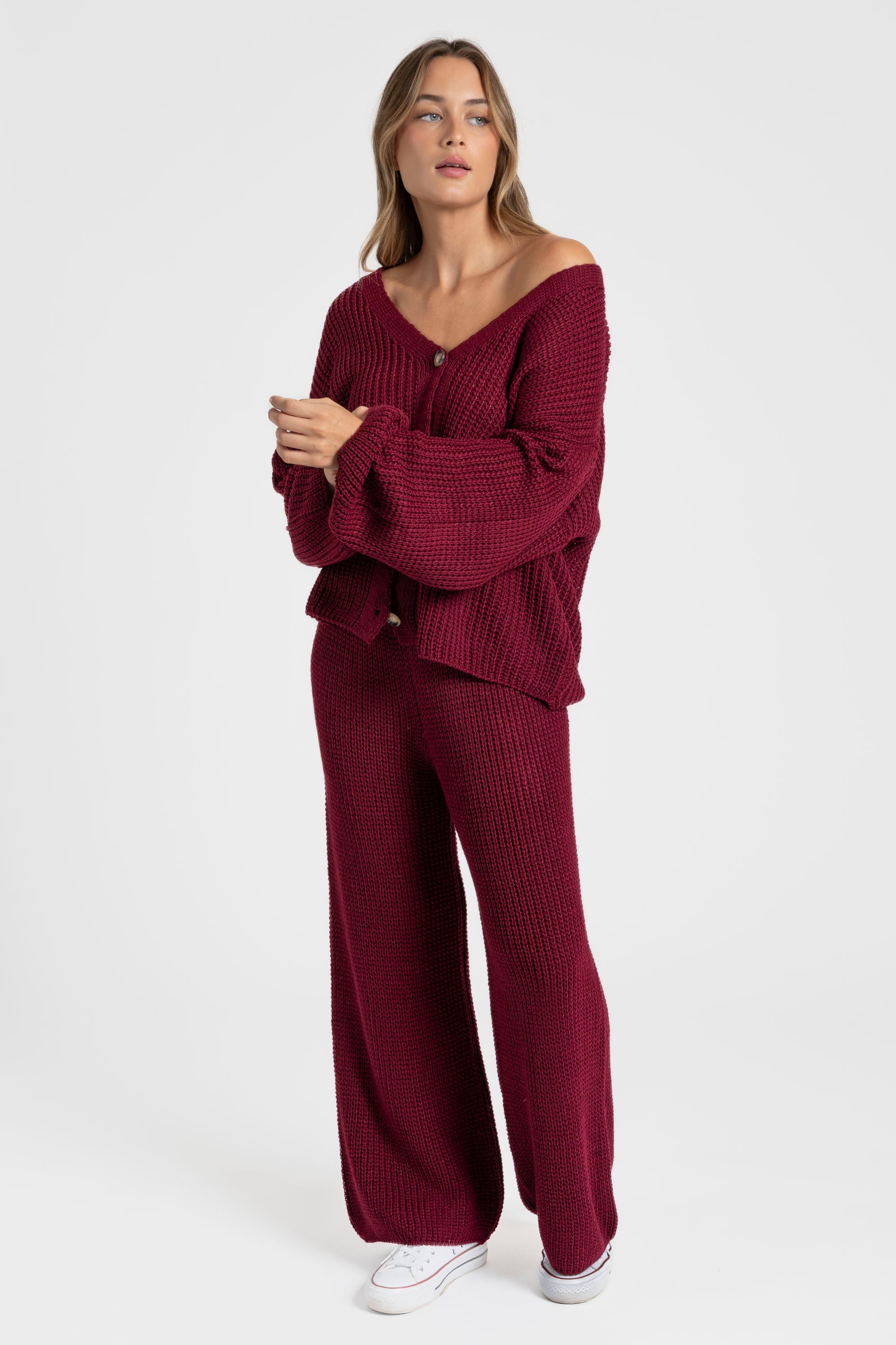 Femme en ensemble maille femme italien, couleur bordeaux, se tenant debout, mettant en avant le col V et le pantalon large.