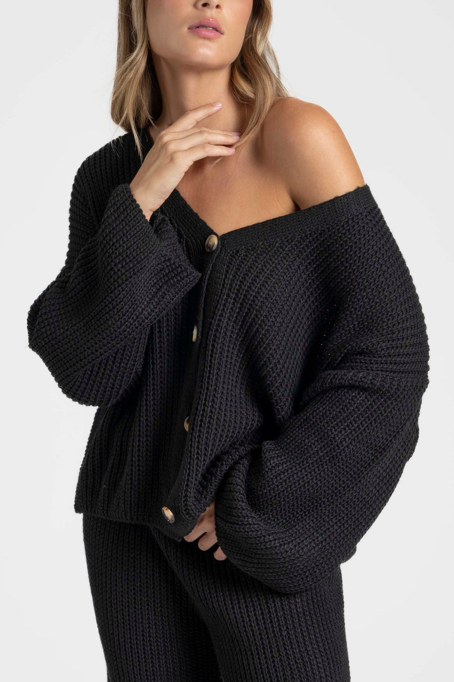 Gros plan sur le haut d'un ensemble maille femme italien, col V boutonné, porté par une femme.
