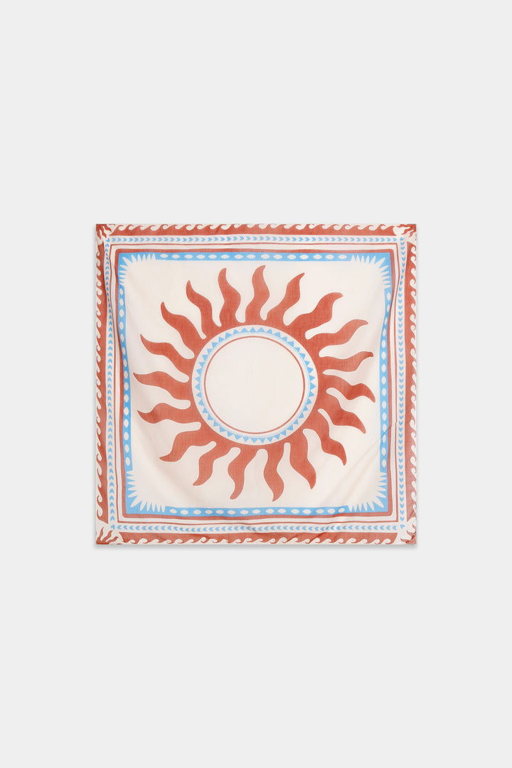 Foulard carré écru présenté à plat, soleil terracotta central et bordures graphiques bleu ciel