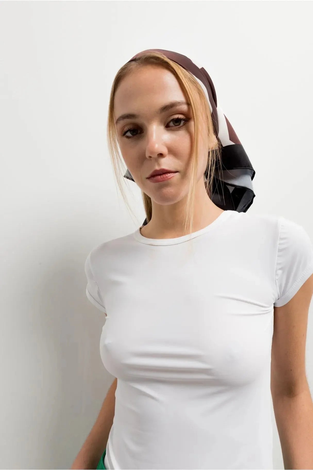 Foulard femme carré imprimé floral marron et blanc cassé porté en bandeau sur une femme, accessoire chic polyvalent.