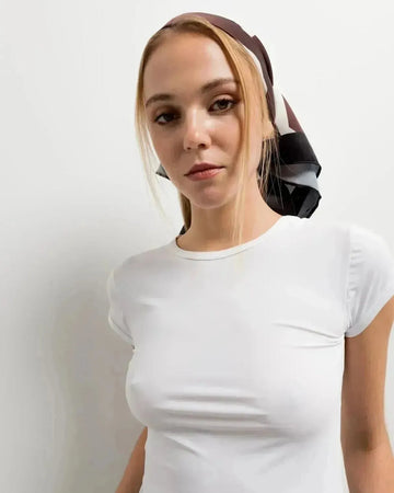 Foulard femme carré imprimé floral marron et blanc cassé porté en bandeau sur une femme, accessoire chic polyvalent.