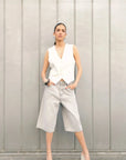 Modèle féminin affichant un gilet sans manches chic en blanc, style tailleur, avec short en denim gris.