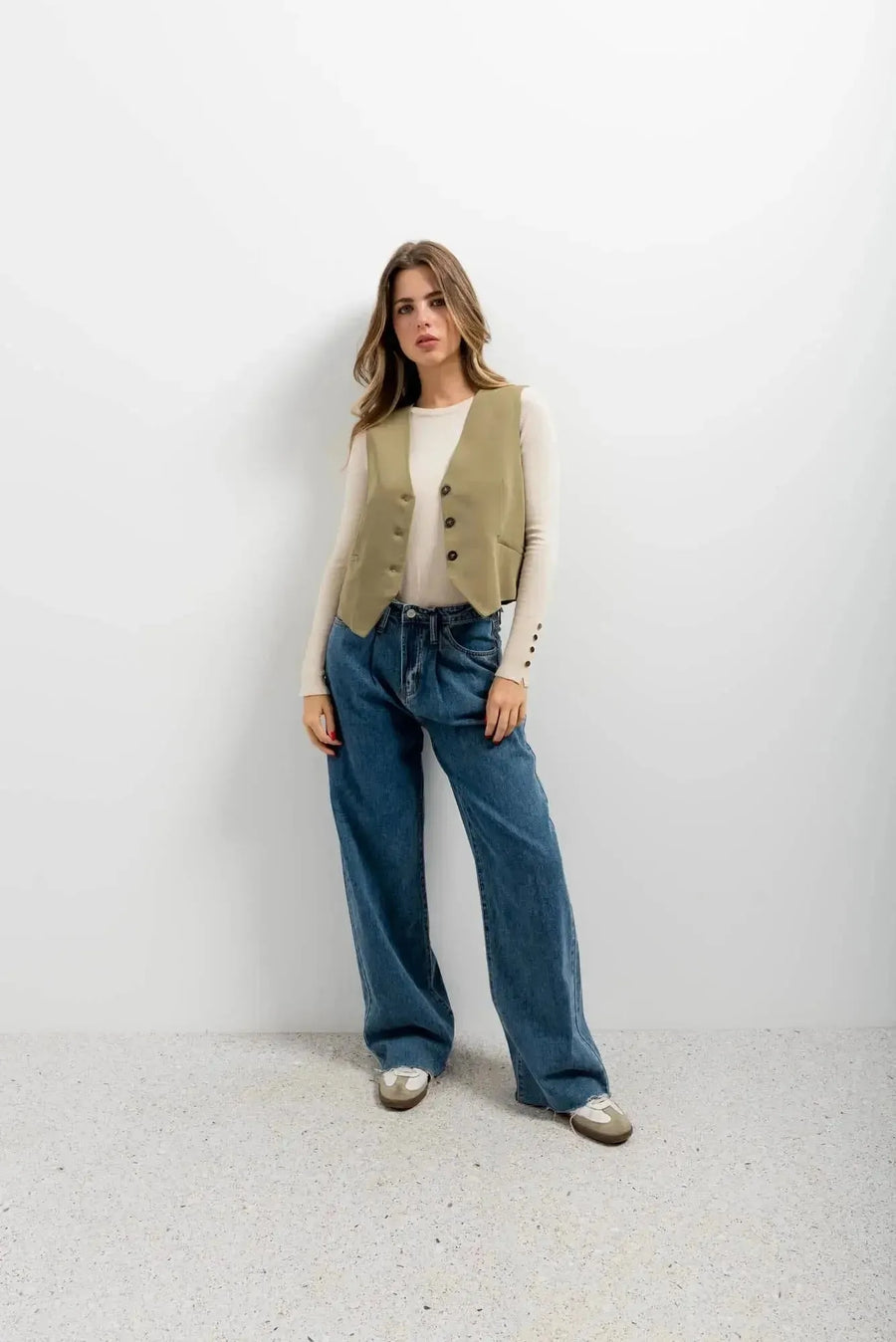 Femme posant avec assurance dans un gilet élégant vert facile à assortir, un gilet court sans manche femme, associé à un look décontracté.