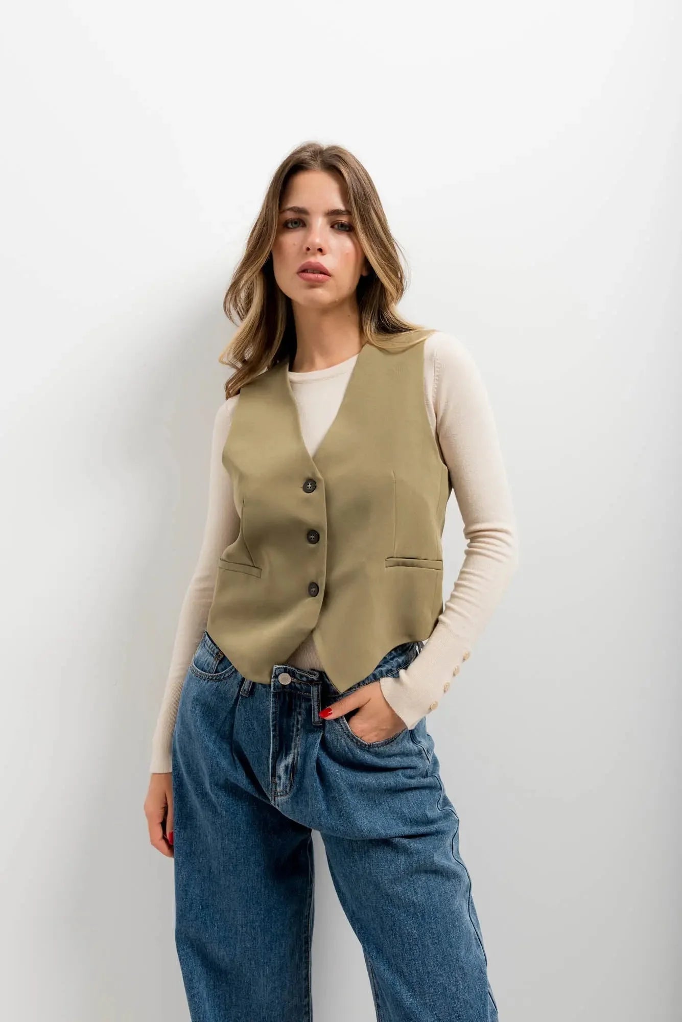 Gilet élégant vert facile à assortir porté avec chemise crème et jean bleu