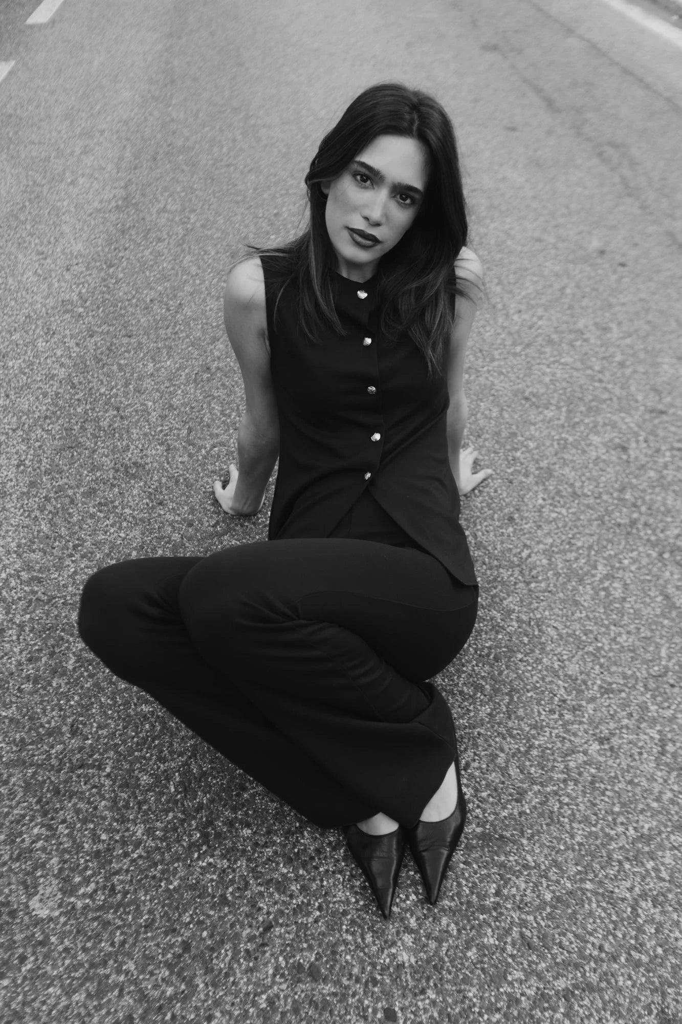 Femme portant un gilet noir sans manches à boutons dorés et chaussures pointues