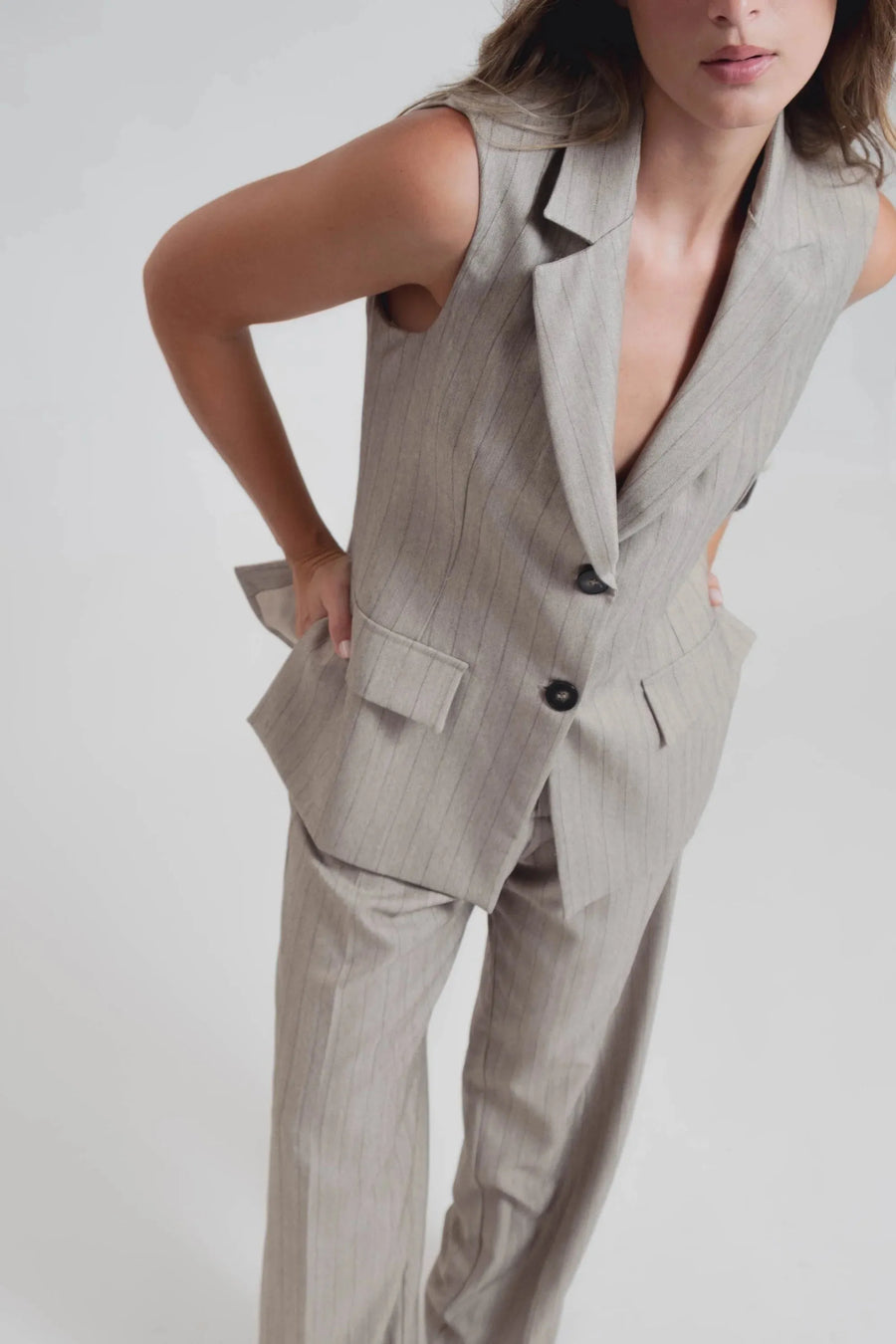 Détail d'un gilet sans manches femme chic à rayures fines élégant, avec boutons contrastés, mettant en valeur un style tailleur moderne. Gilet costume femme parfait pour toutes occasions.