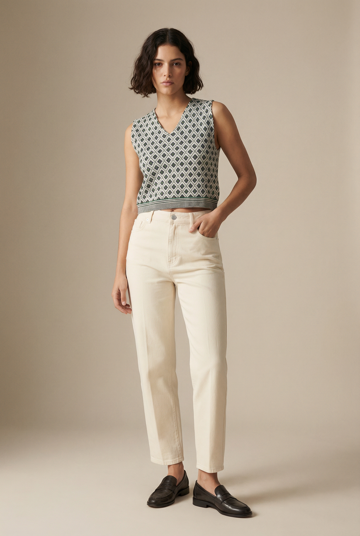 Gilet gris à motifs losanges et col V, porté avec un pantalon écru, vue de face